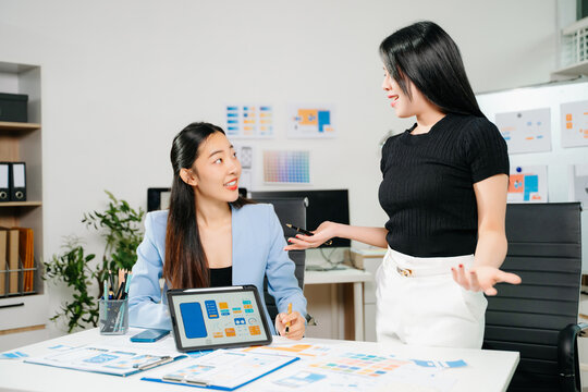 Two UX UI designers brainstorming mobile app wireframes in a modern startup office, showcasing creative teamwork, digital design