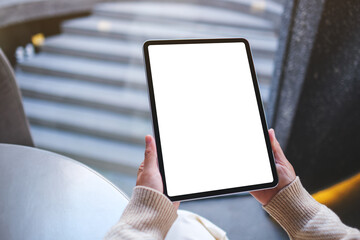 Mockup image of a woman holding digital tablet with blank white desktop screen in cafe