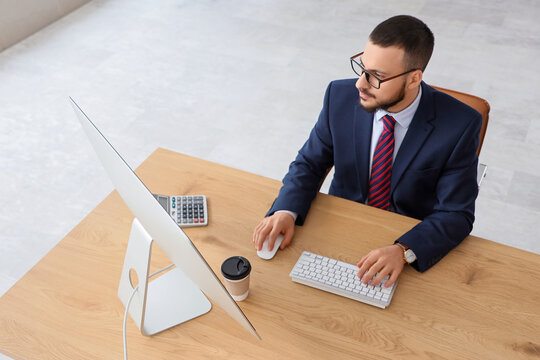 Young businessman using computer to search online in office - Powered by Adobe