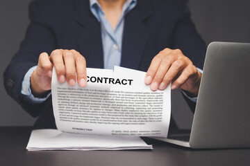 Hand tearing legal contract to end agreement.
