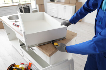 Male worker assembling drawer in kitchen