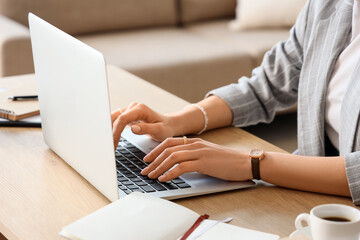 Young businesswoman using laptop to search online at desk in office, closeup