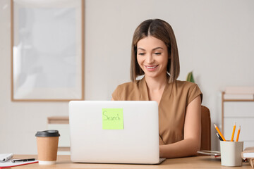 Young businesswoman using laptop to search online in office