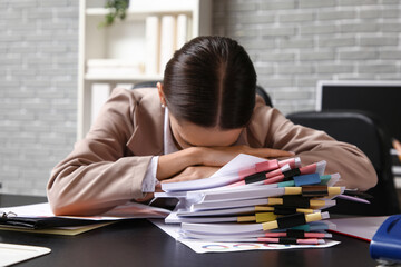 Tired businesswoman with files at table in office
