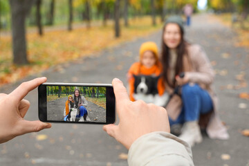 Young man taking picture of his family with dog in autumn park, closeup