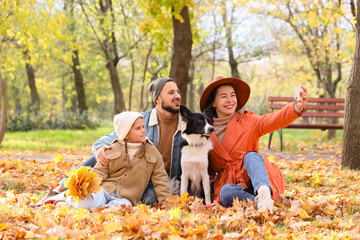 Fototapeta premium Happy family with dog taking selfie in autumn park