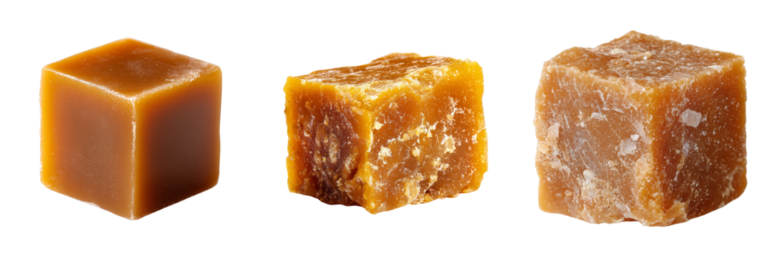 Three blocks of unrefined cane sugar in varying textures and shades of brown isolated on a transparent background
