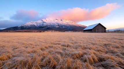 Fototapeta premium Snowy Mountain Backdrop Barn and Frosty Field at Sunrise.