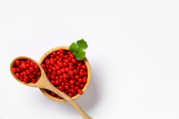 Wooden bowl and spoon with fresh viburnum berries on white background