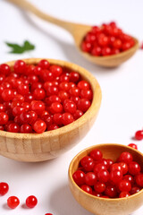 Wooden bowls and spoon with fresh viburnum berries on white background, closeup