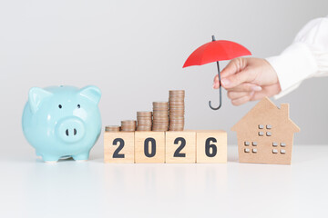 Happy New Year 2026 with red umbrella over money stack. Insurance, real estate, Home loan, tax, investment, mortgage, financial, savings, protection and safety