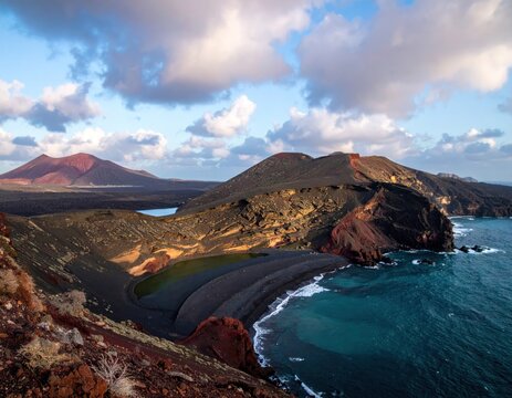 Volcanic coastline with colorful mountains, beach, and turquoise ocean