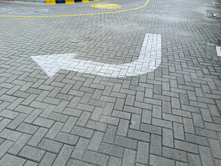 White Directional Arrow on Gray Brick Pavers Road Surface