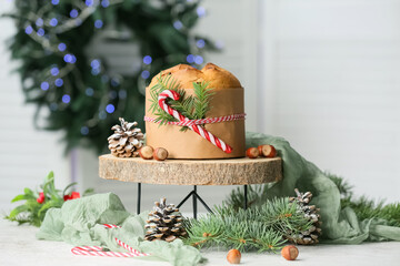Wooden stand with tasty Panettone and Christmas decor on table in living room