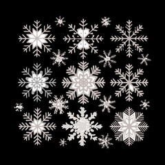 Collection of various silver and white detailed snowflakes falling against a striking dark black color, symbolizing a crisp winter night scene
