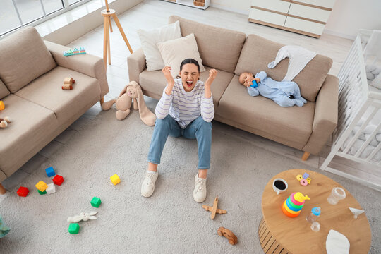 Screaming mother suffering from postnatal depression and her baby on sofa at home, top view