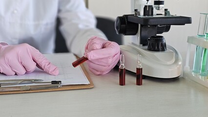 Scientist in laboratory analyzing samples with microscope and test tubes during research concept