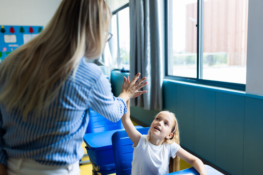 Young woman giving high five to girl in a classroom