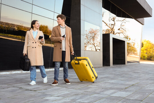 Young couple with passports and luggage walking near airport - Powered by Adobe