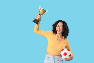 Female African-American sports fan with soccer ball and gold cup on blue background