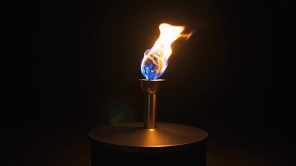 A lit torch with a blue and yellow flame on a metal stand against a dark background with cinematic lighting. - Powered by Adobe