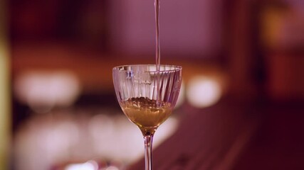 Cocktail making. Cold alcohol drink. Bartender hand straining yellow liquor throw metal sieve. Professional preparing beverage on bar counter.