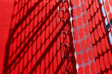 Abstract background of red plastic safety net with strong shadow creating graphic pattern. intense...