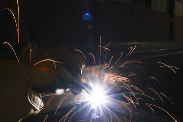 Industrial welder working on metal fabrication with bright light and sparks. skilled worker in construction welding steel, focused on intense, glowing process of metalworking