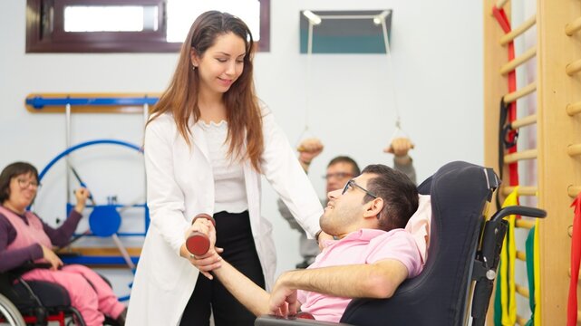 Physiotherapist assisting man with physical disability with rehabilitation exercise