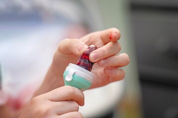 Young mother crushing ripe cherries in a silicone feeder to release juice for baby's first solid food