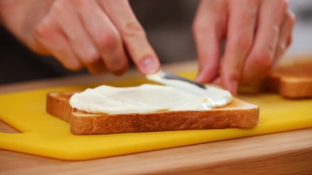 A person spreads cream cheese on toast. A close up shot with detail on the food and action. The scene evokes a feeling of simple pleasures and comfort Stock Video