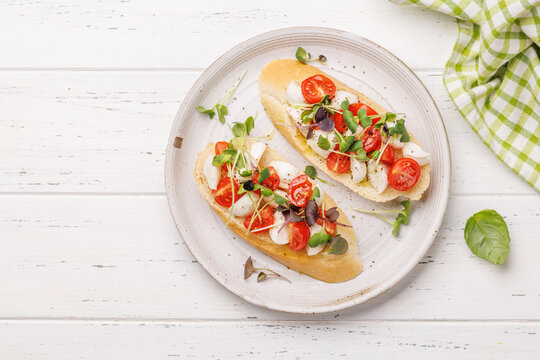 Tasty antipasto toasts featuring classic caprese with mozzarella and tomatoes, and savory prosciutto with herbs