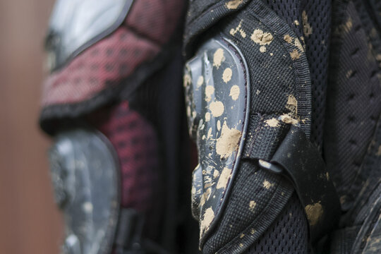 Gritty close up of dirty protective gear covered in mud splatter. This intense detail shows aftermath of an action packed motocross extreme sport competition, highlighting tough pad