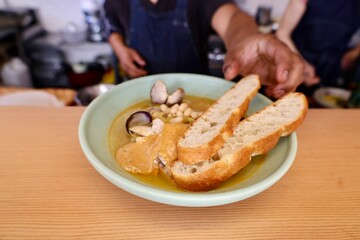 fish and shellfish stew with crostini and chef hand 