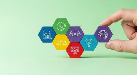 Business strategy development process with colorful hexagonal blocks featuring various icons assembled by a hand.