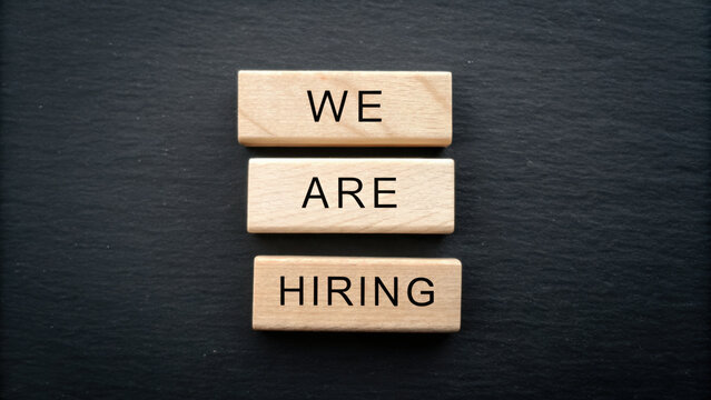 We are hiring message on wooden blocks with black background, symbolizing job opportunity and recruitment concept