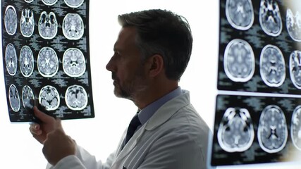A doctor intently analyzes brain scan results in a brightly lit office. The medical professional is reviewing detailed imaging for diagnosis and treatment planning with neuroimaging analysis. - Powered by Adobe