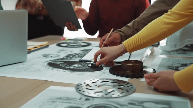 A dynamic team engages in a collaborative meeting in a modern workspace, examining technical drawings and mechanical components, fostering innovation and creativity. SACTR