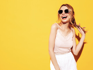 Fototapeta premium Young beautiful smiling female in trendy summer clothes. Sexy carefree woman posing near blue yellow in studio. Positive model having fun. Cheerful and happy. In sunglasses. Screaming and shouting