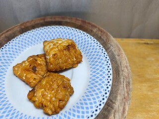 Delicious fried tempeh slices are a good source of plant-based protein for a healthy body. Food photography concepts for products, advertisements, and culinary blog posts. Close-up. Text space.