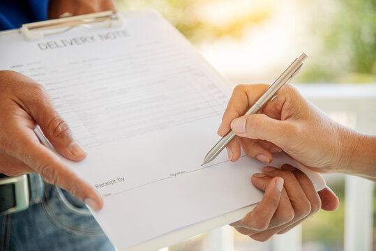 Delivery courier service man deliver package box to woman customer. Mailman shipment holding cardboard package box. Close Up hand receiver signing signature on digital tablet in coronavirus quarantine