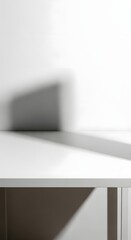 Minimalist white interior with a clean surface and a subtle shadow cast on the wall, emphasizing simplicity and modern design elements