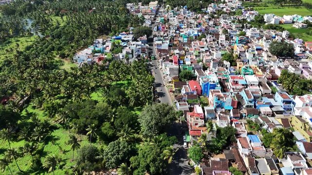 Aerial view of a colorful South Indian town bordered by lush coconut groves and farmlands, showcasing the perfect harmony of rural charm and modern living.