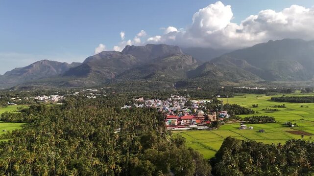 A wide, cinematic aerial shot of Courtallam framed by the towering Western Ghats and lush greenery, highlighting its signature waterfall. Great for travel documentaries and wellness promos.