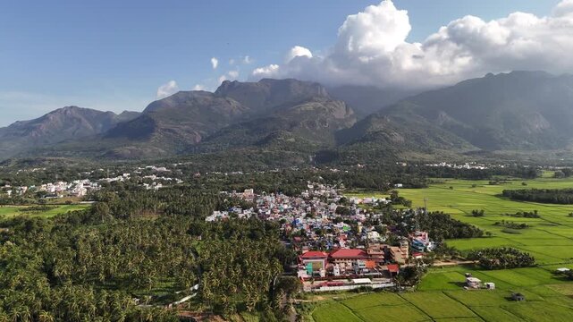 Drone view of Courtallam, Tamil Nadu a serene valley town embraced by dense forests and majestic mountains, with its famous waterfall flowing down the central slopes. Ideal for nature or tourism films