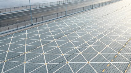 Geometric grid pattern on a large, tiled surface featuring intersecting white lines creating diamond shapes.