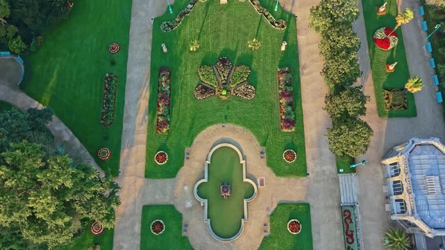 Drone shot in full top-down view flying over the Thabor Park fountain and symmetrical gardens in Rennes, France.
