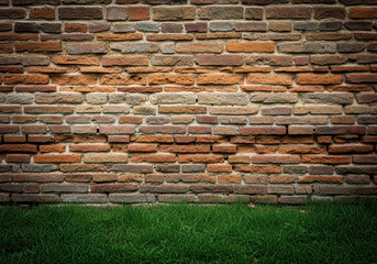 Rustic brick wall with vibrant green grass at the base, showcasing a blend of natural and manmade elements