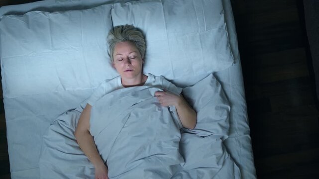 Sleeping man talking in his sleep in bed, top view. Woman suffering from parasomnia sleep disorders.