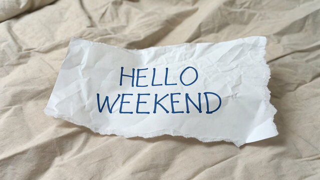 Weekend welcome note on wrinkled paper resting on a cozy fabric background